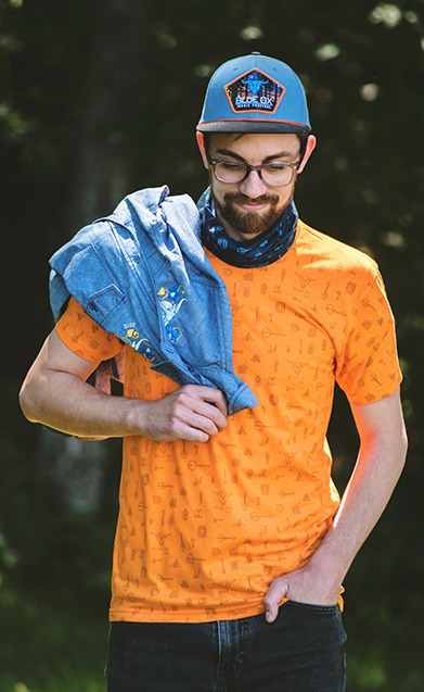 Model wearing Blue Ox hat and tee with a Blue Ox button up over his shoulder