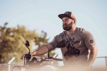 Model wearing a Yamaha Faster Sons baseball tee and hat on motorcycle